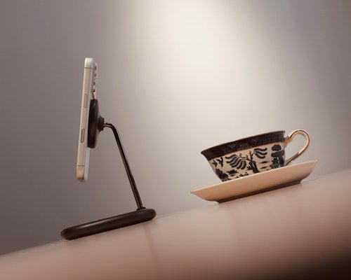 Detail na odložený telefón na pracovnom stole s hrnčekom čaju